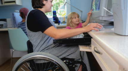 Woman in a wheelchair working with young daughter and son beside her.